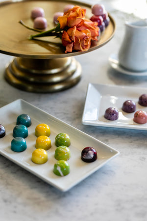 Colorful, shiny chocolate bonbons on various platters